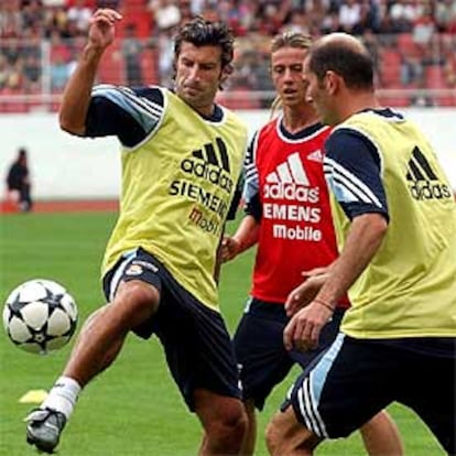 Figo intenta controlar el balón en el partidillo de entrenamiento, ayer, ante Guti y Zidanne.