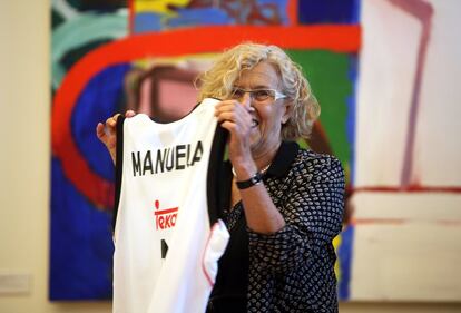 Manuela Carmena recibe una camiseta del Madrid de baloncesto con su nombre