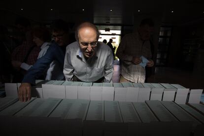 Un hombre busca su papeleta entre las de todos los partidos políticos en el colegio electoral de San Agustín, Madrid.