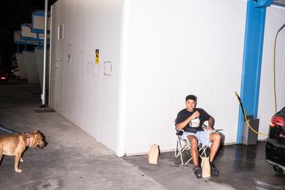 Un joven cenando una hamburguesa en el lavadero del polígono Marconi, donde se organizan quedadas de coches a diario.