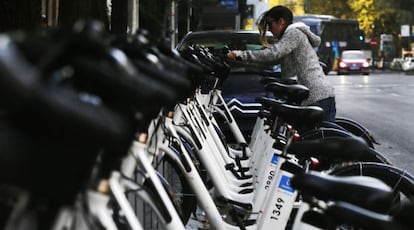 A woman rents a bike at a BiciMAD docking station.