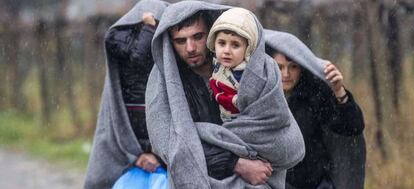 Migrantes caminan bajo la lluvia tras cruzar la frontera griega hacia Macedonia, cerca de la ciudad de Gevgelija.