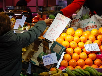 Una consumidora compra en un puesto de frutas y verduras en un mercado de abastos de Madrid.