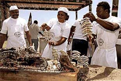 Un grupo de inmigrantes prepara espetos de sardinas en una playa de Málaga.