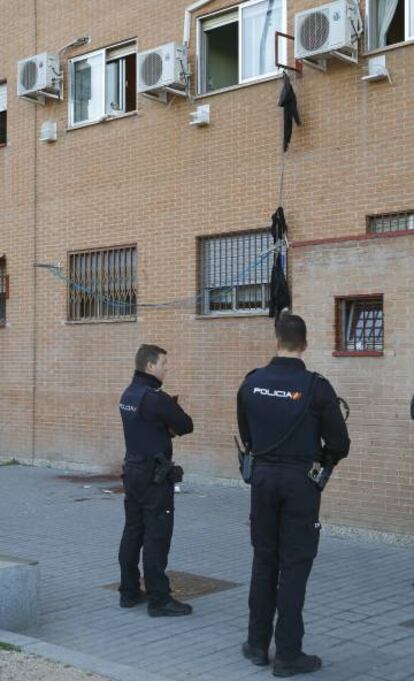 Dos agentes ante el lugar en el que cayó una mujer herida muy grave en Usera.