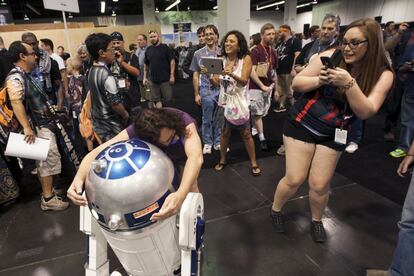 Varios asistentes se toman fotografías con un R2-D2 expuesto en la convención de Anaheim, California.