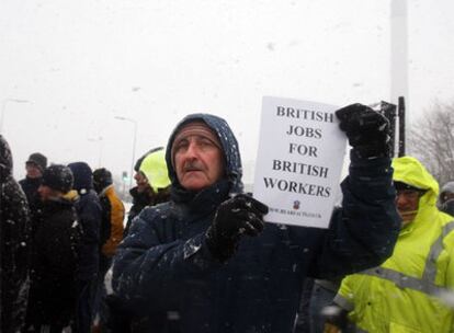 Un huelguista muestra una pancarta a favor del trabajo para los británicos en la refinería de Lindsey.