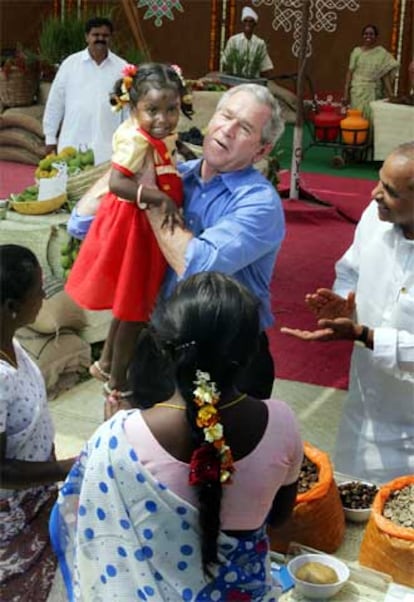 Bush coge en sus brazos a una niña de cuatro años durante su visita a la Universidad de Agricultura de Hyderabad.