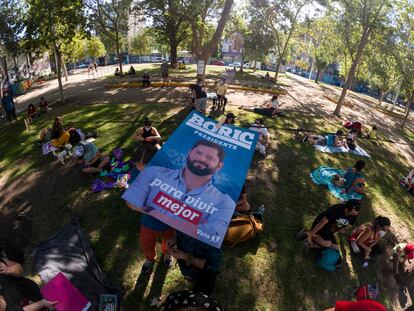Simpatizantes de Gabriel Boric cuelgan una pancarta del candidato en un parque de Santiago
