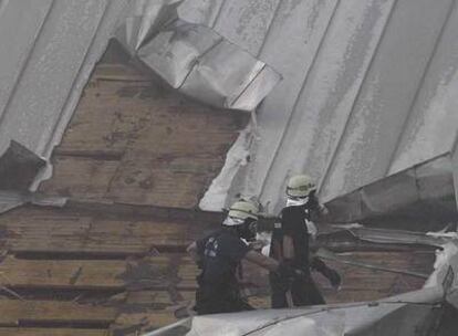 Dos bomberos cortan el tejado para llegar al interior del edificio.