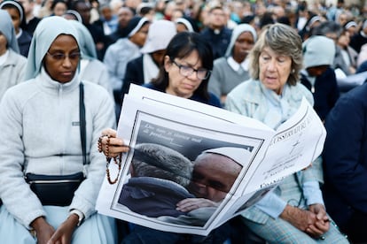 Algunos de los fieles que se han acercado a la plaza de San Pedro rezan y leen sobre la muerte del papa Francisco, este martes en el Vaticano.