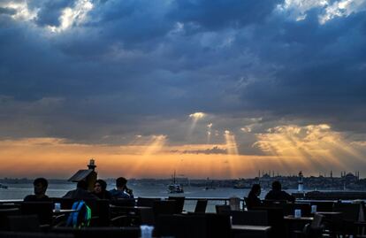 Varias personas disfrutan de la puesta de sol en un café a la orilla del mar en Kadikoy, (Estambul).