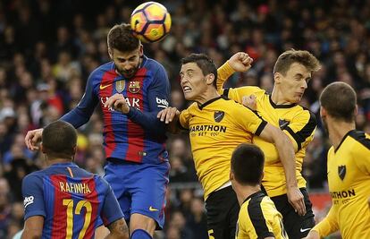 Gerard Piqué (segon per l'esquerra) xuta la pilota davant la pressió dels jugadors del Màlaga.