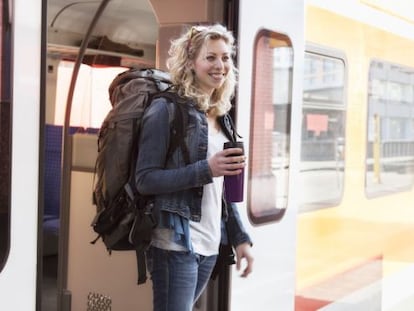 Una joven mochilera se baja de un tren.