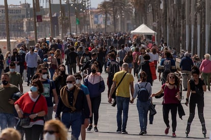 Cientos de personas caminan por el paseo marítimo de la Barceloneta, en Barcelona, este sábado.