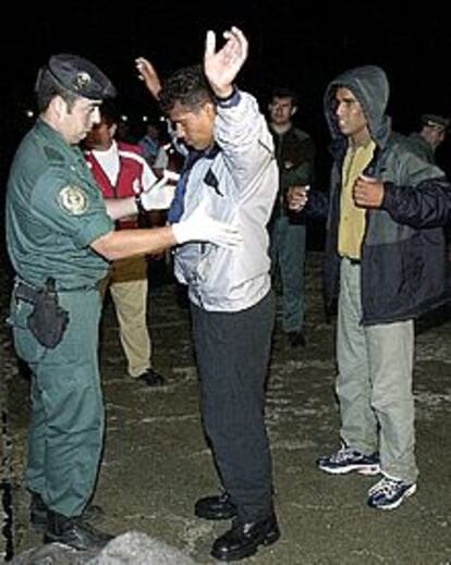 Un guardia civil cachea a uno de los inmigrantes de origen magrebí llegados esta madrugada a Tarifa.