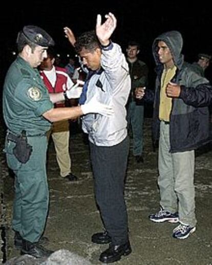 Un guardia civil cachea a uno de los inmigrantes de origen magreb llegados esta madrugada a Tarifa.