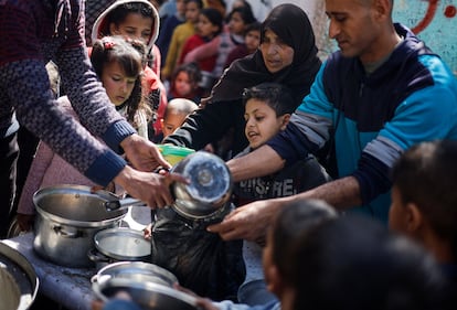 Un grupo de adultos y niños palestinos se agolpan para recibir unas raciones de comida en Rafah, en la Franja de Gaza, este martes.