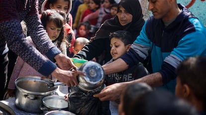 Un grupo de adultos y niños palestinos se agolpan para recibir unas raciones de comida en Rafah, en la Franja de Gaza, este martes.