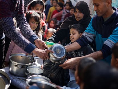 Un grupo de adultos y niños palestinos se agolpan para recibir unas raciones de comida en Rafah, en la Franja de Gaza, este martes.