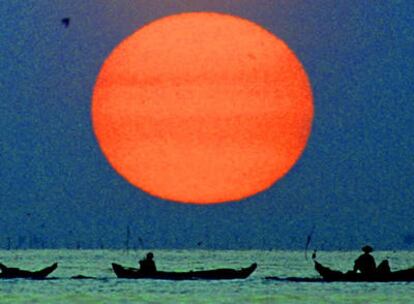 Pescadores de Camboya en sus barcas, en la puesta del sol