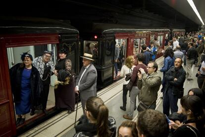 Passatgers a l'andana i a dins del vagó del tren que va inaugurar la línia entre Catalunya i Lesseps el 1924. Alguns d'ells, caracteritzats amb la vestimenta de principis de segle XX i a punt per viatjar de Sagrada Família a Sant Antoni.