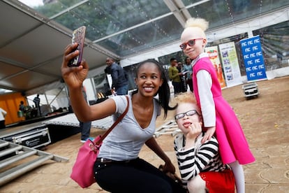 Uma mulher tira uma selfie com as jovens modelos albinas Shirlyne Wangari e Rebecca Zawadi. O concurso, que teve 30 participantes, foi organizado pela Sociedade de Albinismo do Quênia.