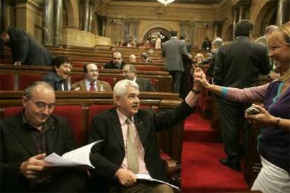 Josep Bargalló (izquierda) lee un documento mientras se saludan Pasqual Maragall y Manuela de Madre en el Parlamento catalán.