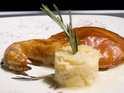 Plato de cochinillo asado con humus de raíz de apio y patatas.