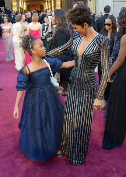 Las actrices Quvenzhané Wallis (i), vestida por Armani Junior, y Halle Berry, que luce un Versace. Wallis es la décima actriz negra en ser nominada. Berry obtuvo el premio en 2002. Berry ha explicado que le pidió a Donatella Versace un traje inspirado en su idea de una 'chica Bond'.