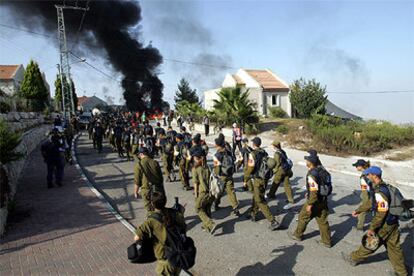Soldados israelíes se dirigen al asentamiento de Homesh, donde, al fondo, arden las barricadas.