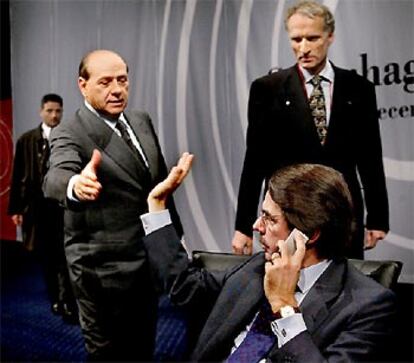 Berlusconi tiende la mano a Aznar en un momento de la cumbre. Les observa el ministro danés para Europa.