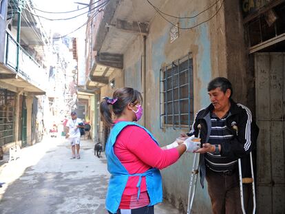 Una militante de Barrios de Pie reparte comida a un habitante de la villa 1-11-14 considerado grupos de riesgo ante la covid-19