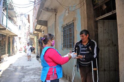 Una militante de Barrios de Pie reparte comida a un habitante de la villa 1-11-14 considerado grupos de riesgo ante la covid-19