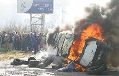 Trabajadores de Izar en Sevilla, junto a una furgoneta y neumáticos ardiendo, durante los enfrentamientos de ayer con la policía.
