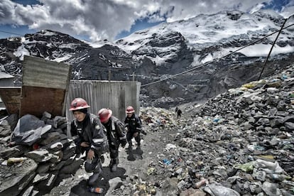 Unos mineros vuelven de la mina entre montañas de escombros y basura.