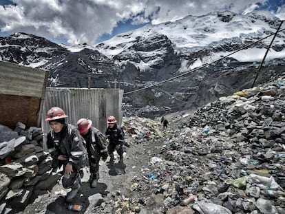 Unos mineros vuelven de la mina entre montañas de escombros y basura.