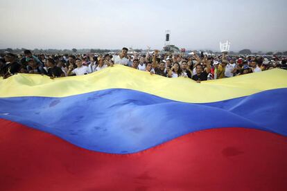 Un grupo de personas extiende una bandera venezolana mientras esperan el inicio del concierto, cuyo propósito es apoyar la asistencia solicitada por Guaidó.
