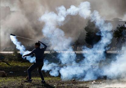 Manifestante palestino arroja un bote de gas lacrimógeno hacia las tropas israelíes en la ciudad cisjordana de Ramala.