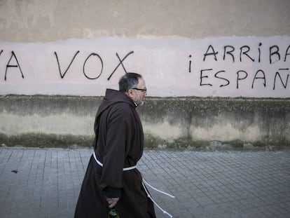 Un monje pasa ante unas pintadas favorables a Vox, en Barcelona.
