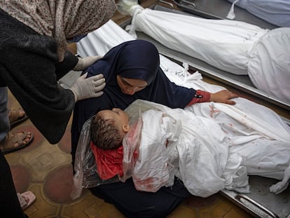 Una mujer sostenía a su hijo mientras extendía la mano para tocar el cuerpo de su marido, ambos muertos en un bombardeo del ejército israelí en la franja de Gaza, en el hospital de Jan Yunis, el martes.