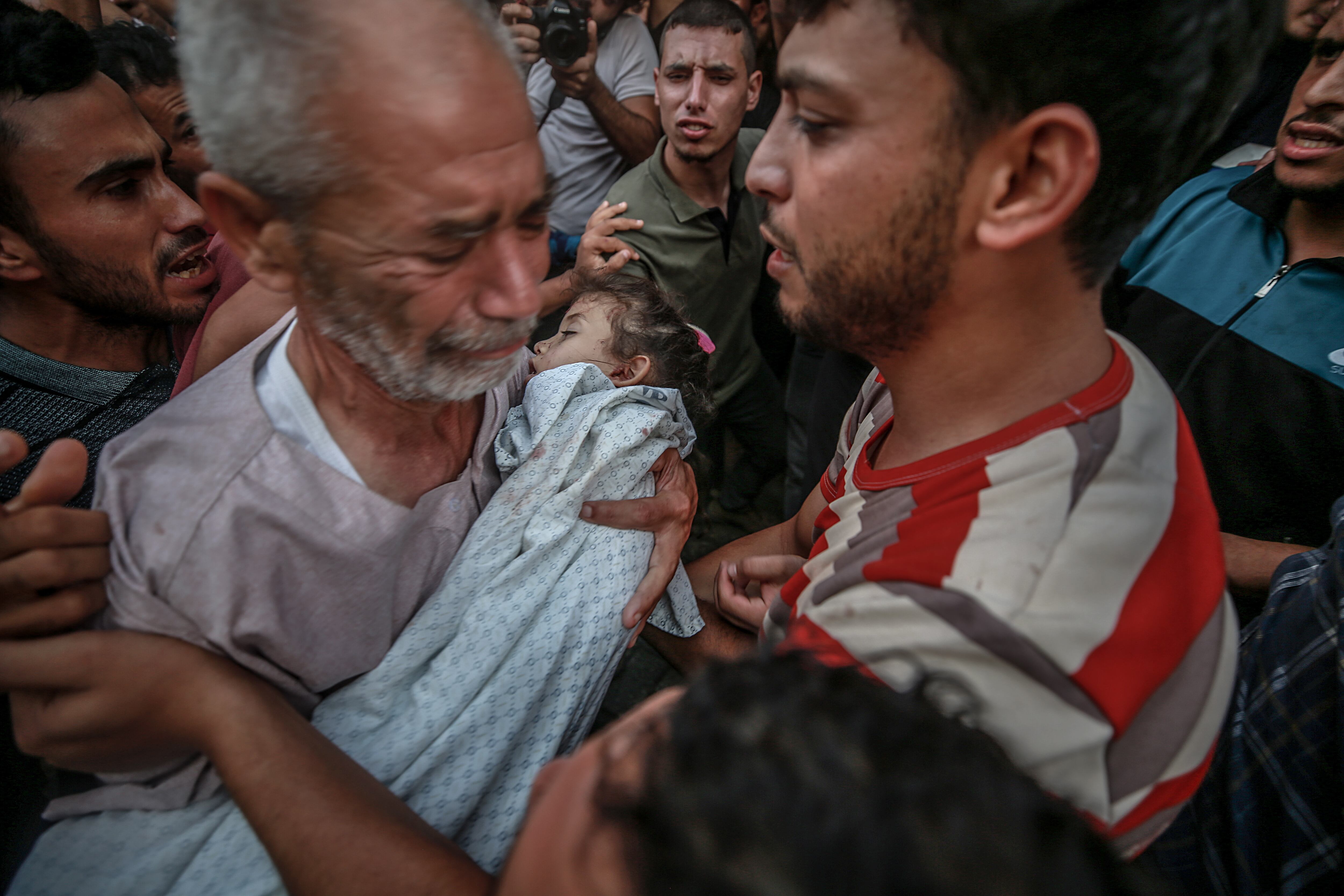 El abuelo de Alaa Qadoum, niña de cinco años muerta en un bombardeo, llevaba el cadáver de su nieta durante su funeral, el viernes en la ciudad de Gaza.