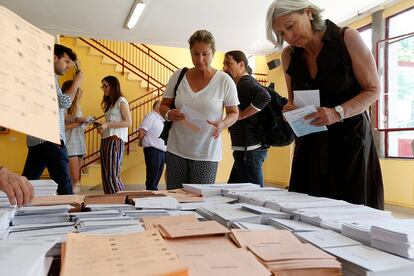 Varios votantes eligen las papeletas de su opción en el colegio Bernadette de Aravaca, Madrid. La participación ha sido la más baja de la historia de la democracia, según los datos provisionales.