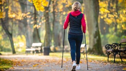 Mujer practicando marcha nórdica en un parque.