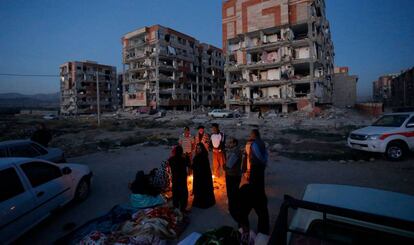 Residentes junto a unos edificios destruidos en Sarpol-e Zahab (Irán).