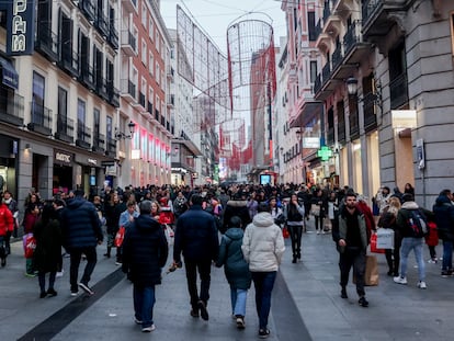 Cientos de personas, con compras, en la calle comercial de Preciados, en Madrid.