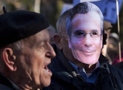 Un hombre protesta por el juicio a Garzón junto a otro con una careta con el rostro del juez esta mañana frente al Supremo