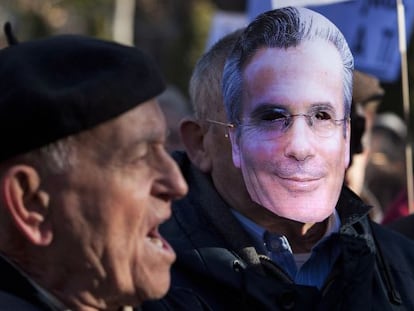 Un hombre protesta por el juicio a Garzón junto a otro con una careta con el rostro del juez esta mañana frente al Supremo