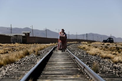 "Esta imagen muestra la vida de la mujer en el altiplano boliviano, que es muy dura. Estas vías del tren están en desuso y son utilizadas como un camino para ir de un sitio a otro. La mujer transporta a su espalda desde alimentos y cosas para la casa hasta a los bebés, usan esas telas para todo. La foto sirve para ver las condiciones de vida de un lugar tan árido y desértico, y también representa el trabajo de la mujer: camina grandes distancias, es una parte activa de la economía familiar, trabajan la tierra, cuidan animales...".