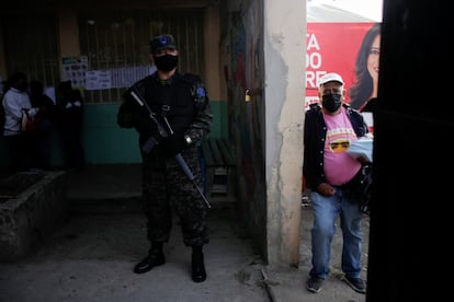 Un miembro del Ejército hace guardia en un colegio electoral mientras la gente hace fila para votar. Honduras se preparó para una posible jornada violenta cuando se abrieron las urnas.